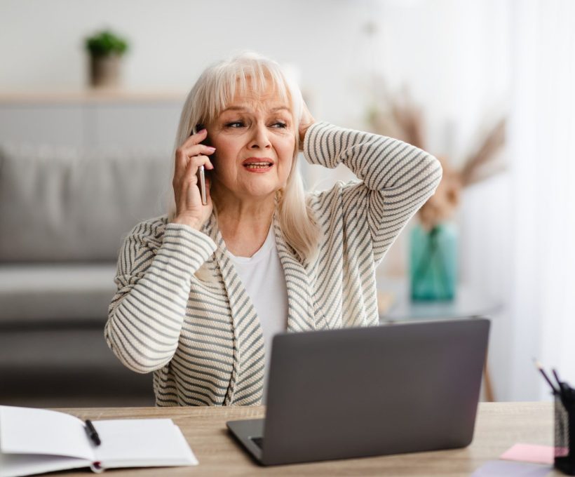 Surprised shocked senior woman talking on mobile phone